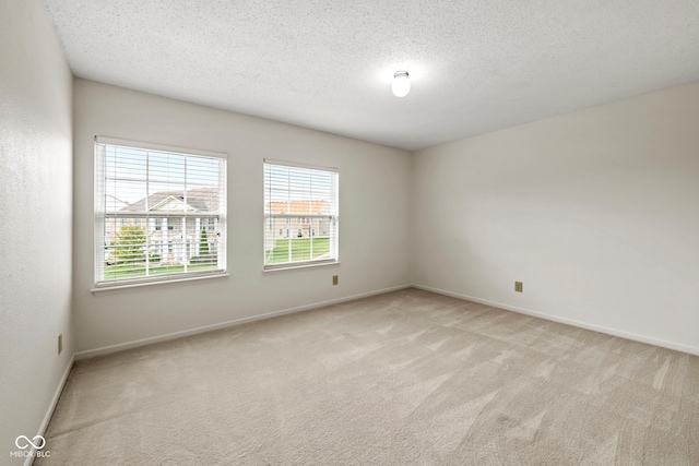 spare room with a textured ceiling and light colored carpet