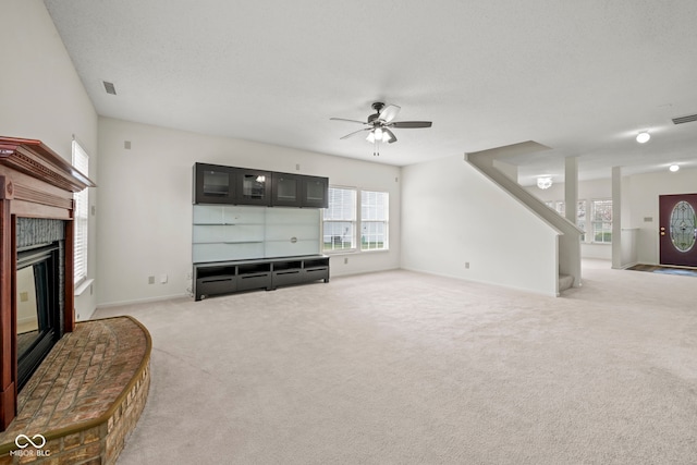 living room featuring a textured ceiling, ceiling fan, light colored carpet, and a brick fireplace