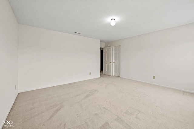 spare room with light colored carpet and a textured ceiling