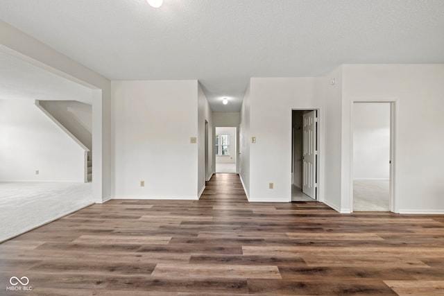 spare room featuring a textured ceiling and dark hardwood / wood-style flooring