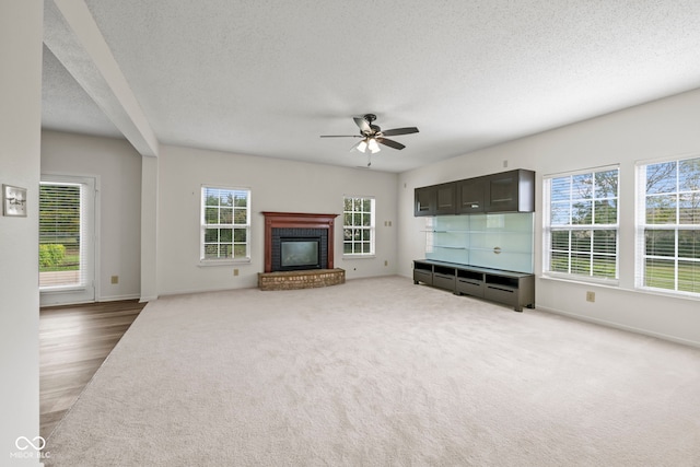 unfurnished living room with ceiling fan, a fireplace, and plenty of natural light