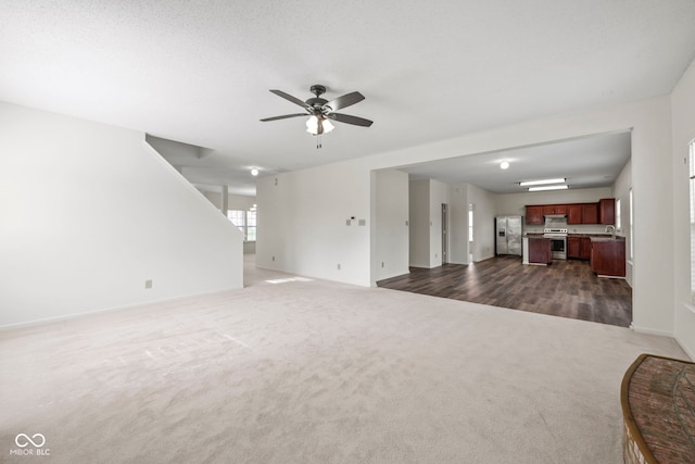 unfurnished living room with dark colored carpet and ceiling fan