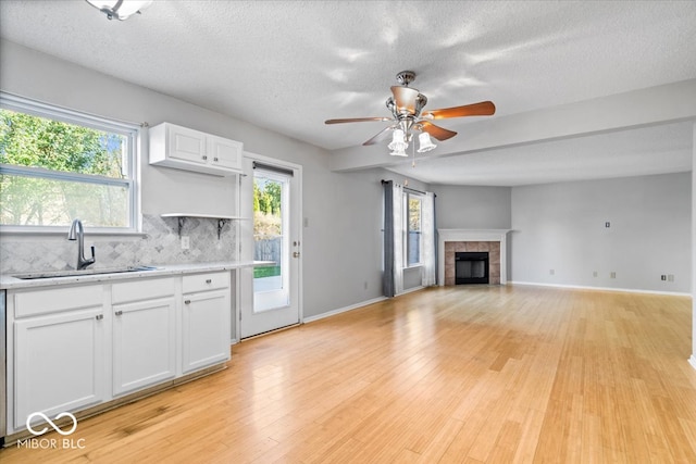 kitchen featuring a textured ceiling, light wood-type flooring, white cabinetry, and sink