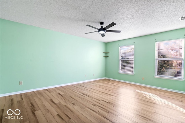 spare room featuring ceiling fan, light wood-type flooring, and a textured ceiling