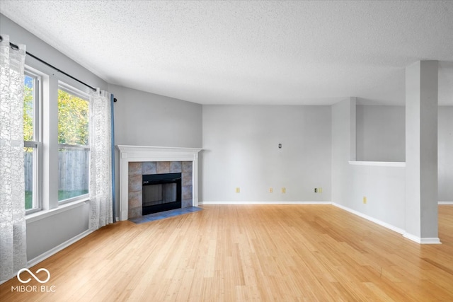 unfurnished living room featuring a tile fireplace, hardwood / wood-style floors, and a textured ceiling