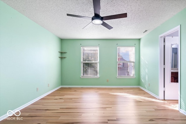 empty room with a textured ceiling, light wood-type flooring, and ceiling fan