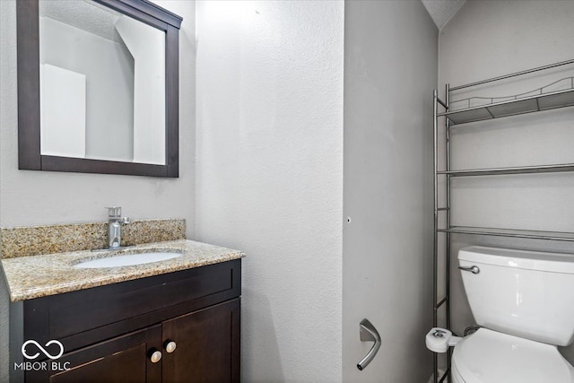 bathroom featuring vanity, a textured ceiling, and toilet