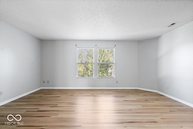 unfurnished room featuring light hardwood / wood-style flooring and a textured ceiling