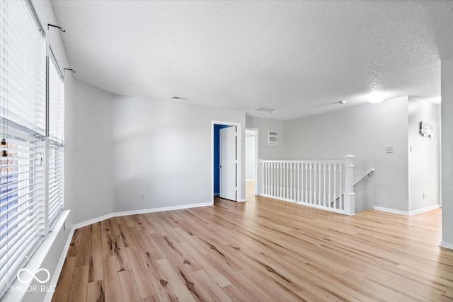 unfurnished room with a textured ceiling and light hardwood / wood-style floors