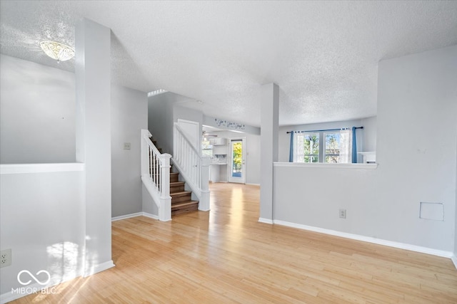 unfurnished room featuring light hardwood / wood-style flooring, a textured ceiling, and an inviting chandelier