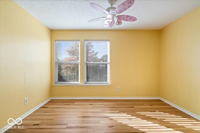 empty room with ceiling fan, light hardwood / wood-style flooring, and a textured ceiling