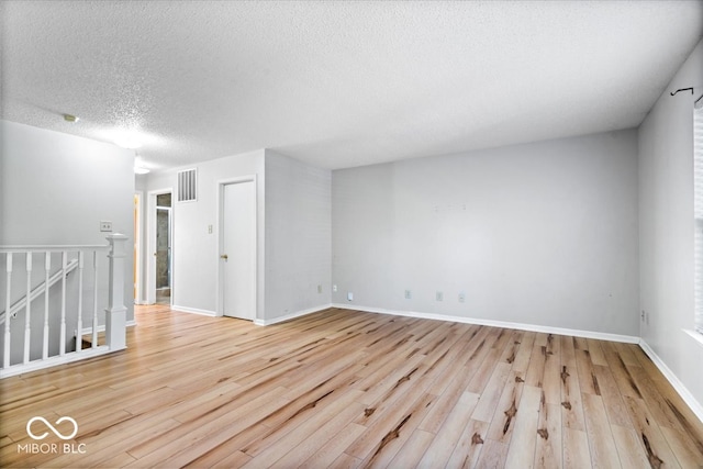 empty room with a textured ceiling and light wood-type flooring