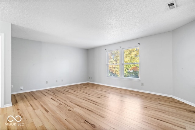 unfurnished room with a textured ceiling and light hardwood / wood-style flooring