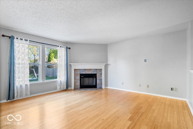 unfurnished living room featuring a fireplace, a textured ceiling, and light hardwood / wood-style floors