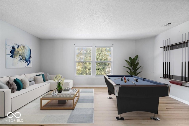 game room with a textured ceiling, light wood-type flooring, and billiards