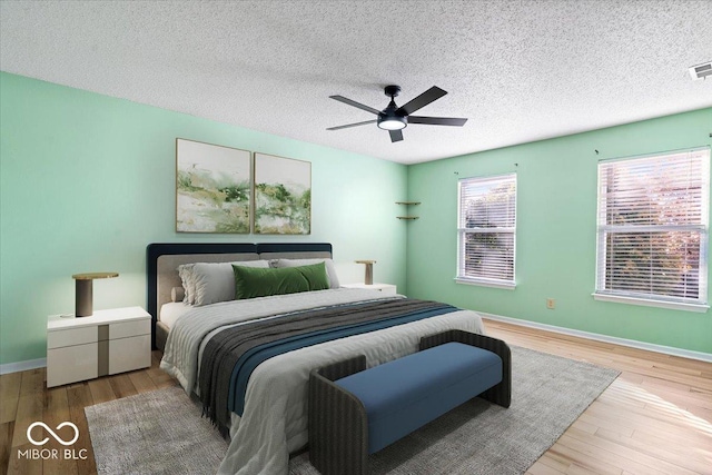 bedroom with ceiling fan, a textured ceiling, and light hardwood / wood-style flooring