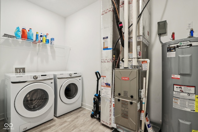 clothes washing area with light wood-type flooring, water heater, and washer and clothes dryer