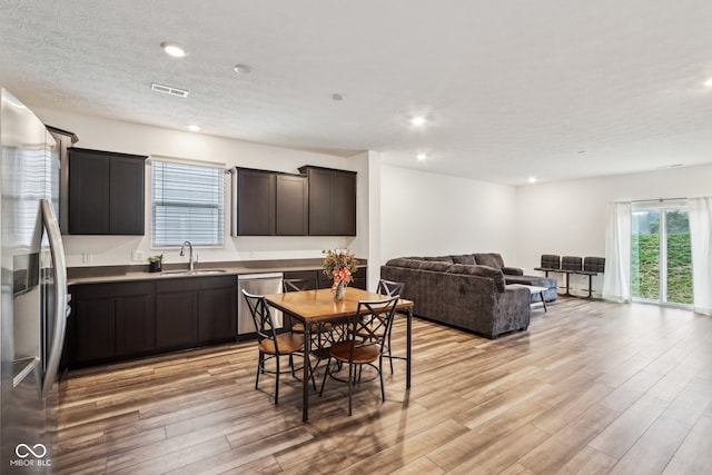 dining area featuring light hardwood / wood-style flooring, a textured ceiling, and sink