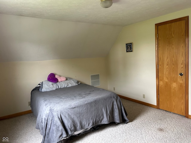 bedroom with carpet floors, a textured ceiling, and lofted ceiling