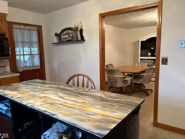 carpeted dining area featuring a textured ceiling