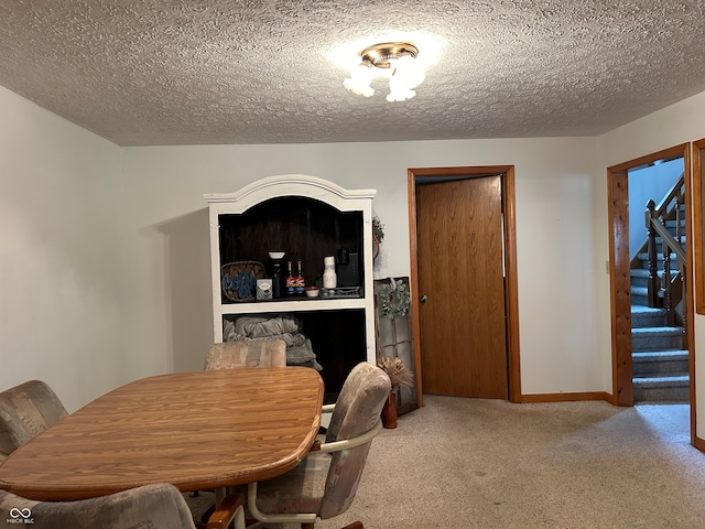 carpeted dining room featuring a textured ceiling