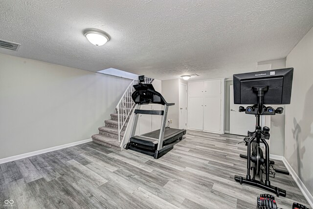 workout area featuring a textured ceiling and light wood-type flooring