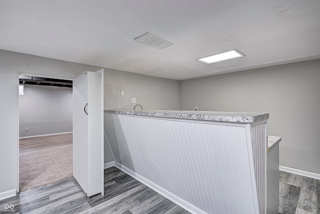 corridor with a textured ceiling and hardwood / wood-style flooring