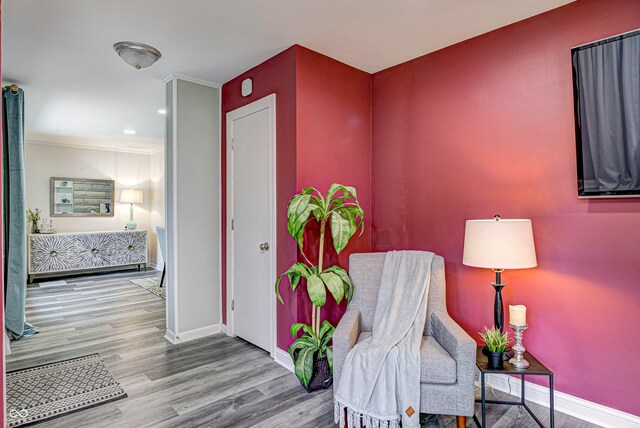 sitting room featuring wood-type flooring and crown molding