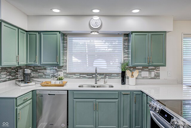 kitchen featuring appliances with stainless steel finishes, decorative backsplash, green cabinetry, and sink