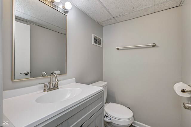 bathroom with a paneled ceiling, vanity, and toilet