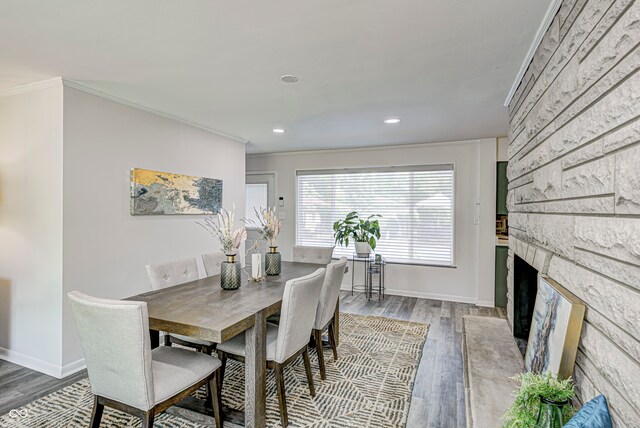 dining room featuring crown molding, a fireplace, and hardwood / wood-style flooring