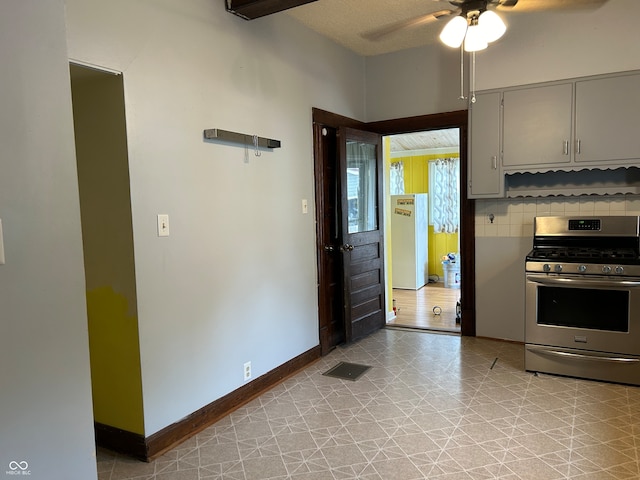 kitchen with ceiling fan, white refrigerator, stainless steel gas range oven, light tile patterned floors, and backsplash