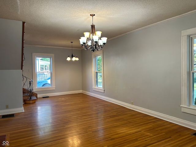 empty room with ornamental molding, hardwood / wood-style flooring, a chandelier, and a textured ceiling