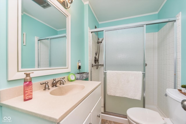 bathroom with a shower with door, vanity, toilet, and crown molding