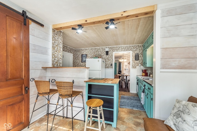 kitchen with butcher block counters, kitchen peninsula, a kitchen bar, a barn door, and white fridge