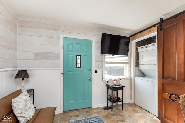 foyer entrance with stacked washer and clothes dryer and wooden walls