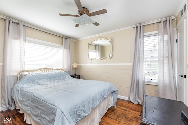 bedroom with dark hardwood / wood-style flooring, wooden walls, ceiling fan, and crown molding