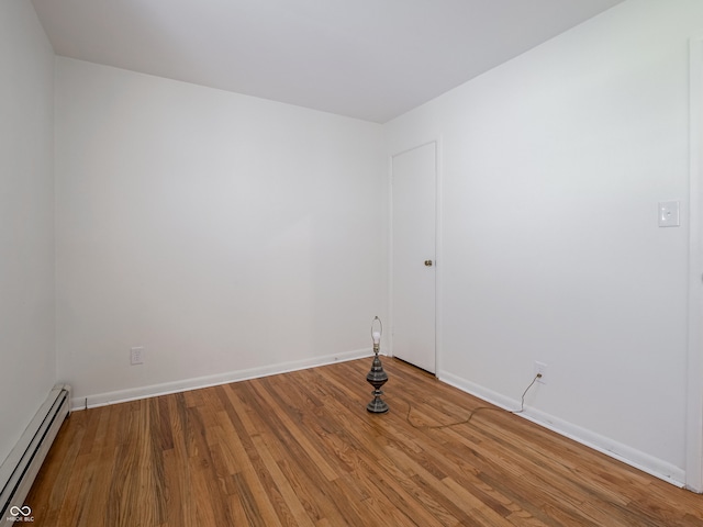 unfurnished room with hardwood / wood-style floors and a baseboard heating unit