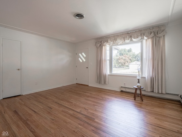 unfurnished room with a baseboard radiator and hardwood / wood-style floors