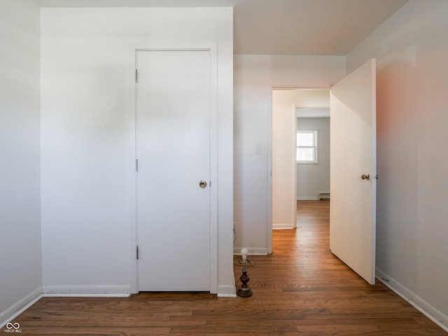 hallway featuring a baseboard heating unit and wood-type flooring