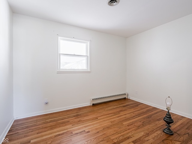 empty room with a baseboard radiator and light hardwood / wood-style floors