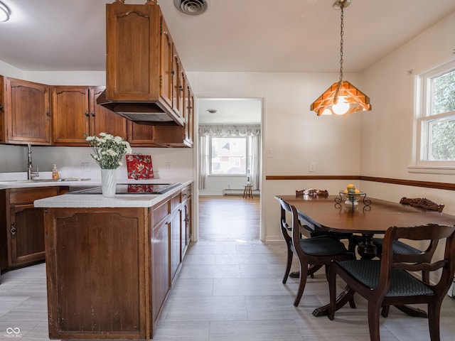 kitchen featuring black electric stovetop, a kitchen island, decorative light fixtures, and sink