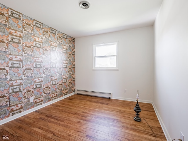 empty room with a baseboard heating unit and hardwood / wood-style floors