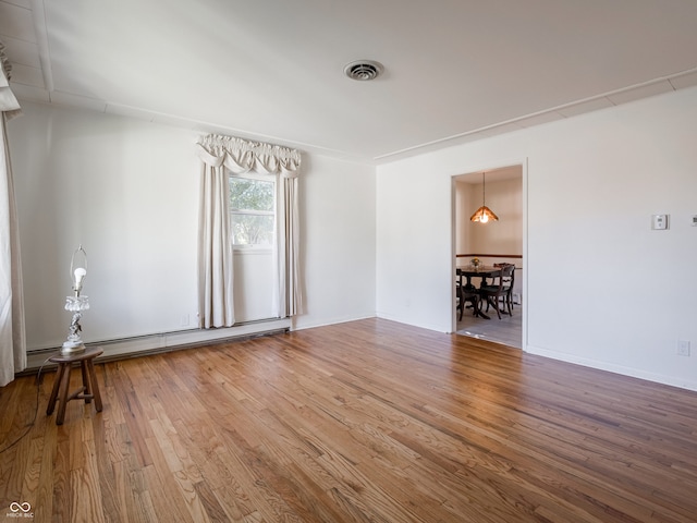 empty room with wood-type flooring and a baseboard radiator