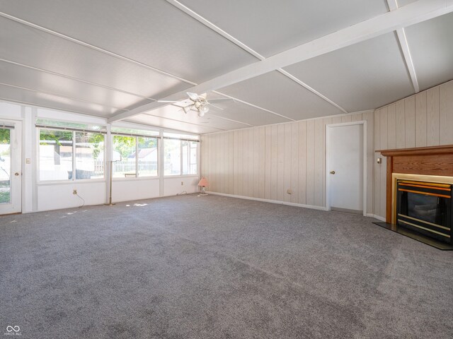 unfurnished living room with carpet, ceiling fan, and wood walls