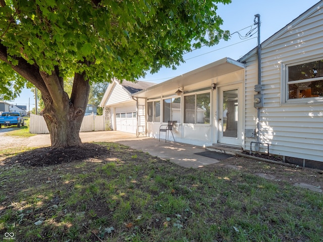 view of front of house featuring a sunroom, a front yard, and a garage