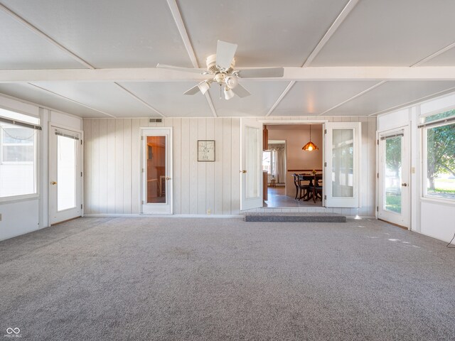 unfurnished room with wood walls, ceiling fan, and light colored carpet