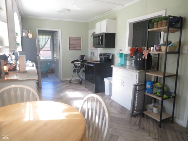 kitchen with appliances with stainless steel finishes, parquet floors, ornamental molding, and white cabinets