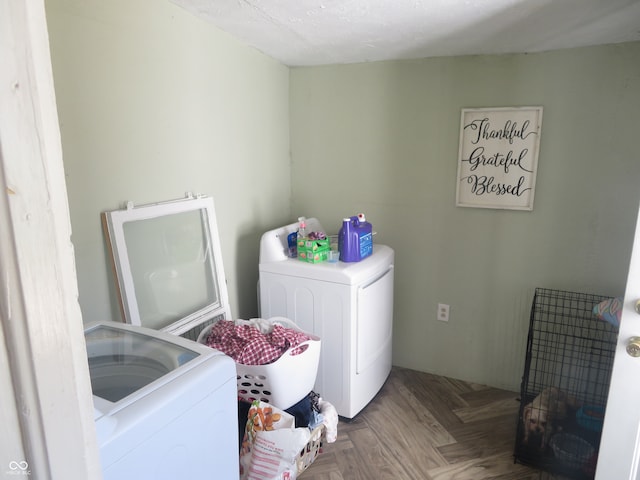 clothes washing area featuring washer and clothes dryer and parquet flooring