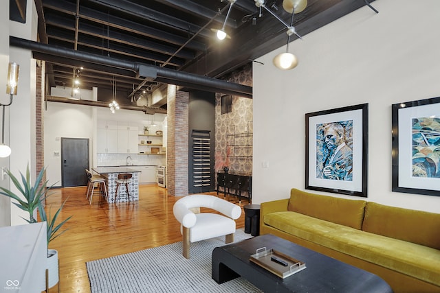 living room featuring a towering ceiling, hardwood / wood-style floors, and sink